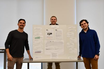 Three students stand with their poster created for a data competition.