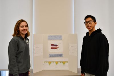 Two students pose next to their data competition poster.