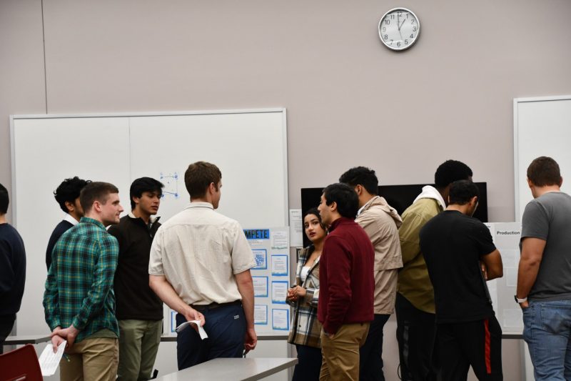 Group of students gather to discuss poster during judging of data competition.