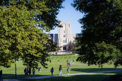 Students walk across the Drillfield in front of Burruss Hall. 