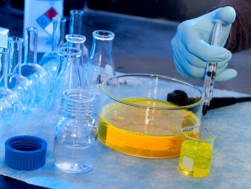 gloved hand draws yellow liquid into syringe