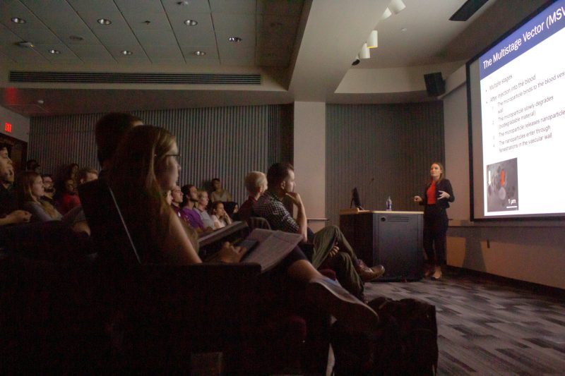 Wolfram gives lecture by podium, audience in dark foreground