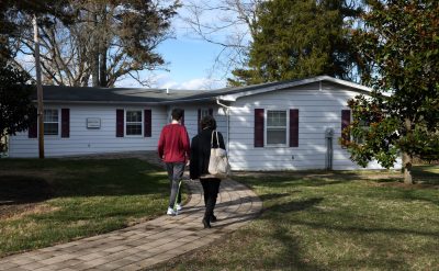 Mother and teenage child walk up path to Autism Clinic building