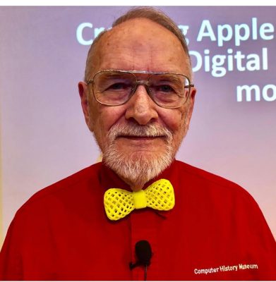 man wears red shirt and yellow plastic bowtie and looks at camera