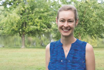 woman in blue sleeveless shirt smiles with duck pond in background