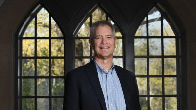 Kevin Pitts in navy blazer inside with gothic windows in the background