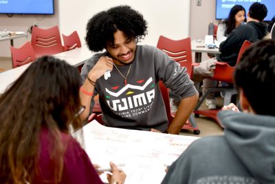 students sit at tables and draw out plans