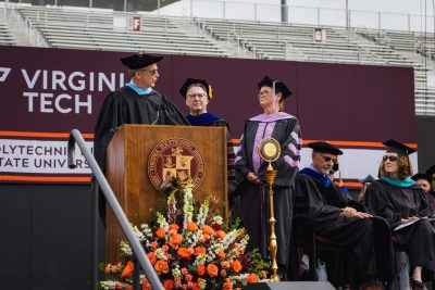 older woman in graduation attire stands at podium to receive an award