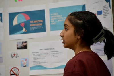 Student, shown in profile, stands in front of poster.