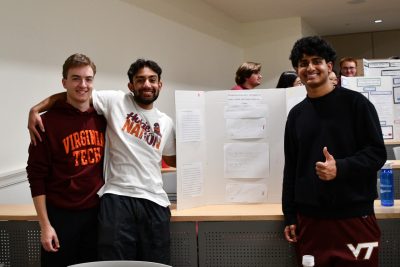 Three students stand next to their poster.