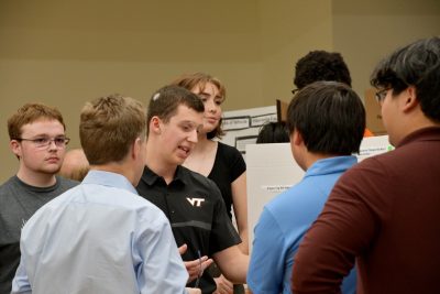 Student in middle of group presents poster.