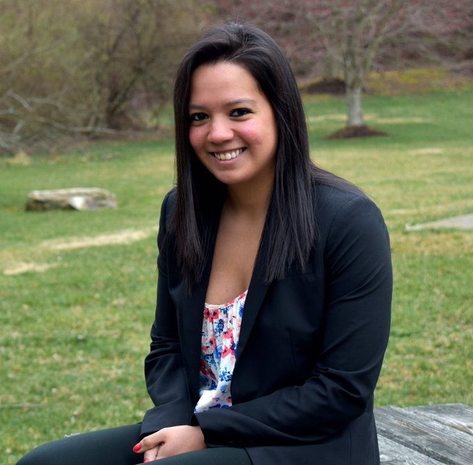 Erika Hernandez sits on picnic bench with grassy background