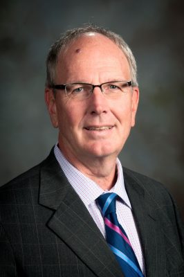 portrait of Neil Hauenstein with gray backgroudn