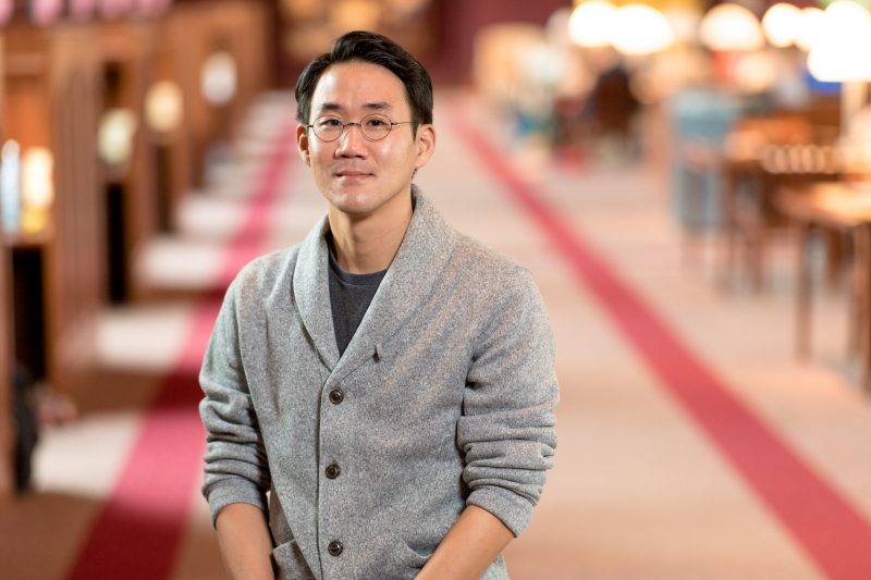 Tae-Ho Lee in gray sweater with Torgersen Bridge library in background