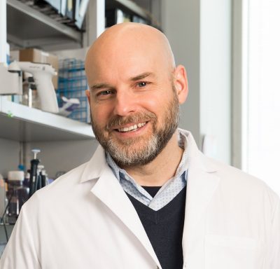 bald man with beard in lab coat portrait in a laboratory