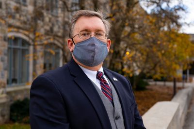 Ron Fricker, senior associate dean for the Virginia Tech College of Science,  poses wearing a mask and dress suit at the Pylons.