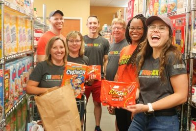 A group of Hershey employees display packages of Reese's peanut butter cups and Cap'n Crunch cereal at a food pantry.