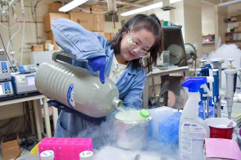 Grad student Matson Lab female scientist pours liquid nitrogen into a container