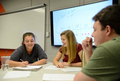 students sit around table working on math problems