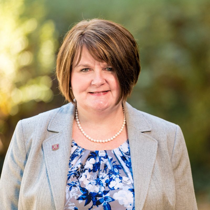 Susan Haymore headshot with blurred greenery background