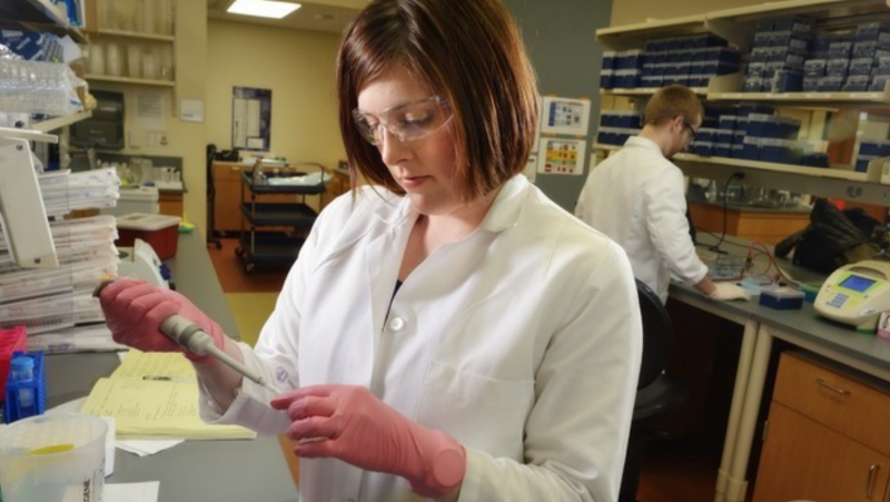 female student research pipets into tube