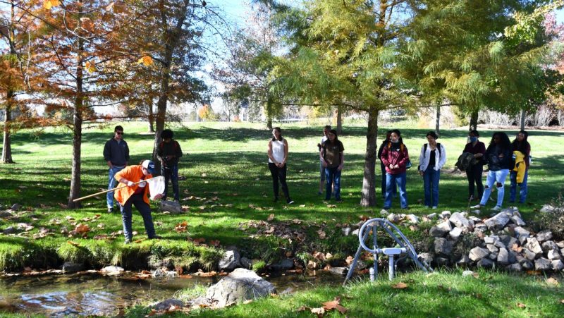 biology professor leads nature walk to duck pond and holds a net