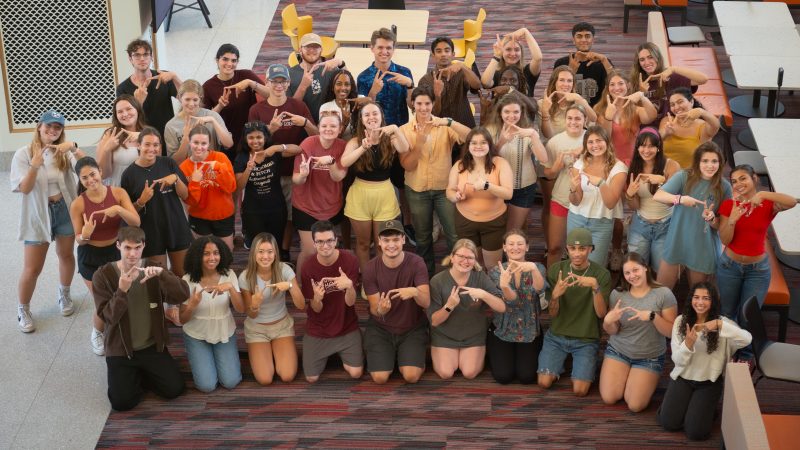 a large group of students gather and pose outside for a photo