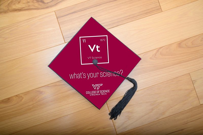 What's your science grad hat graduation cap on wood floor with "What's your science?" mortar board