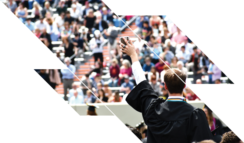 male student holds up phone to crowd during commencement celebration