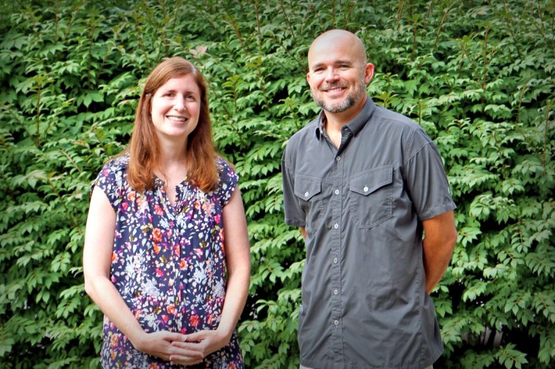 Dana Hawley and Bill Hopkins outside in front of green bushes