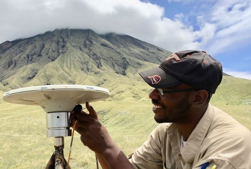 Josh fixing equipment with large Tanzanian volcano in background