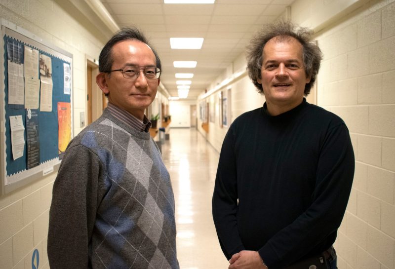 Tastu and Djordje stand with cinderblock hallway receding in background 