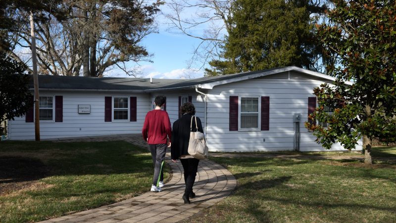 Mother and teenage child walk up path to Autism Clinic building