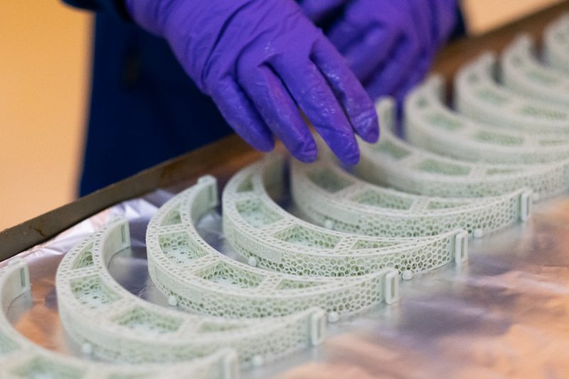 face shields face shield parts are laid out on a table. Researcher with gloved hands counts them.