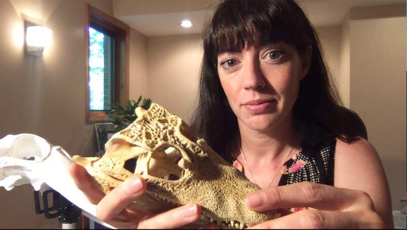 woman holds animal skull up to camera in her home