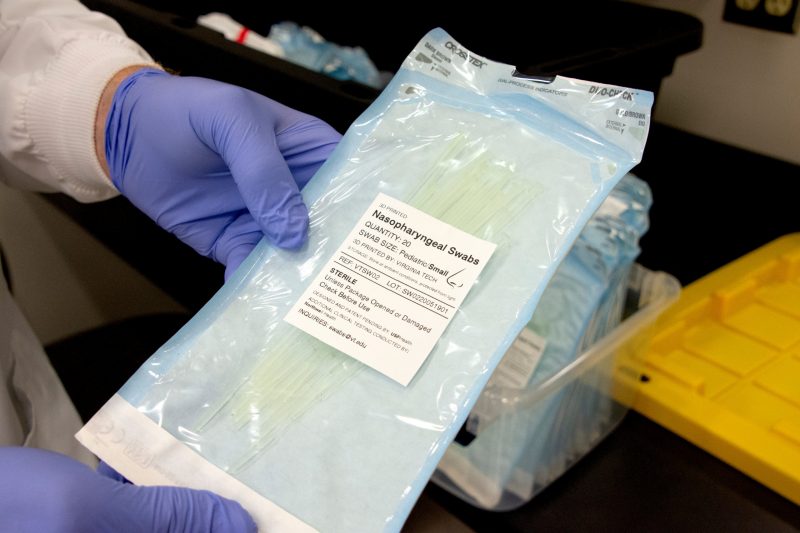 gloved hands hold a bag of sealed swabs