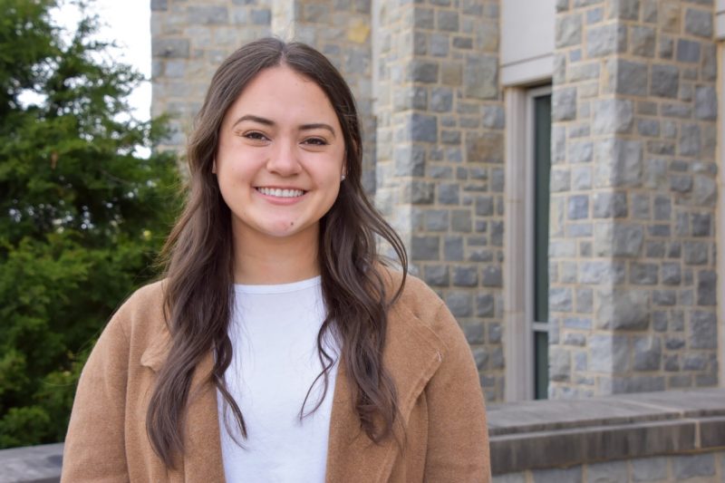 woman smiles at camera in front of Hokie Stone building