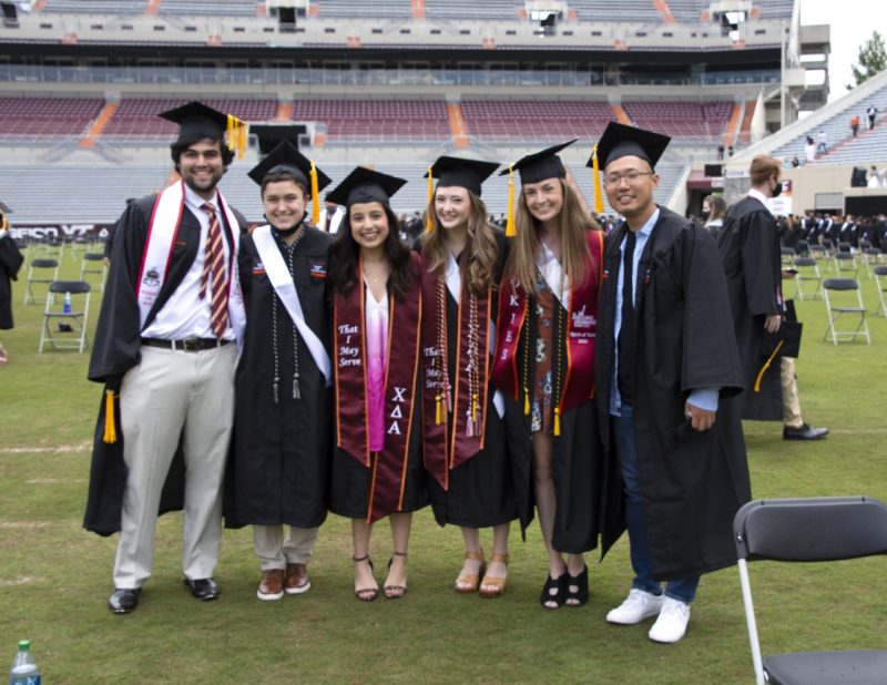 graduating seniors smile and pose with linked arms inside Lane Stadium