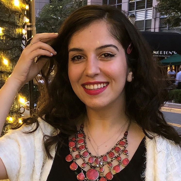 woman smiling and pushing hair away from face with city street in background