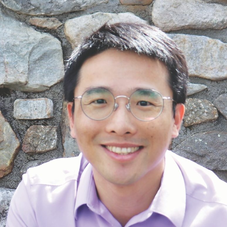 Lin portrait in front of stone wall wearing purple dress shirt.