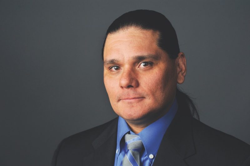 Bowers portrait with suit and tie and gray backdrop.