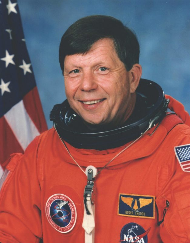 portrait of man in orange astronaut suit with American flag in the background