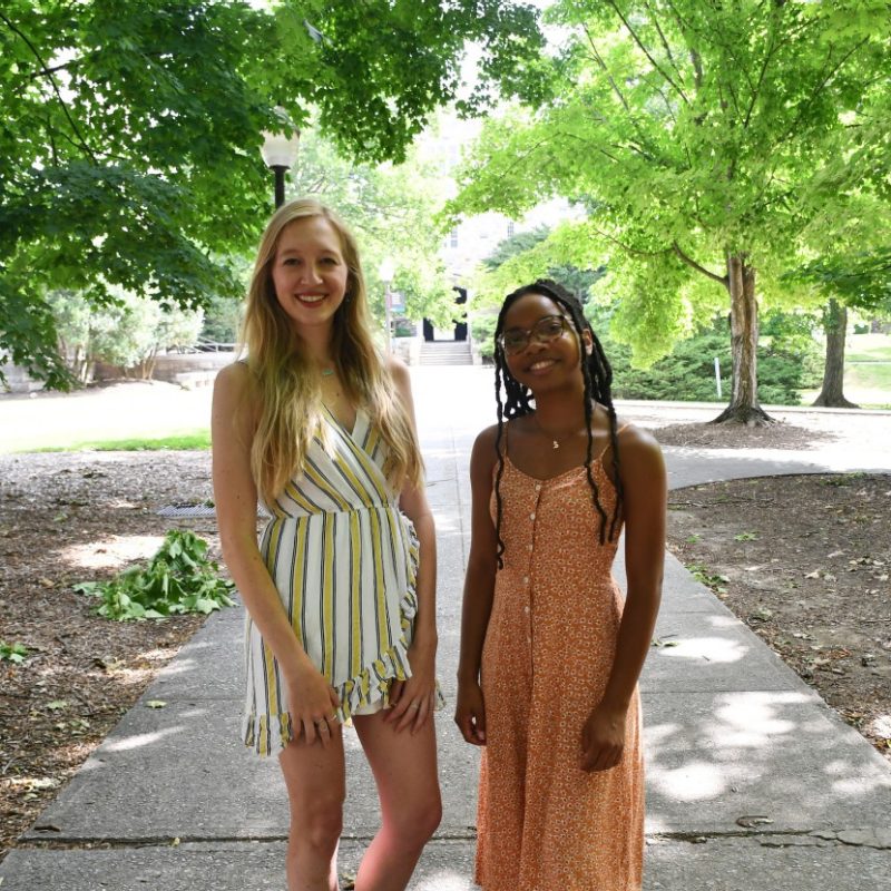 Janey and Brianna two women pose on shaded sidewalk during the summer