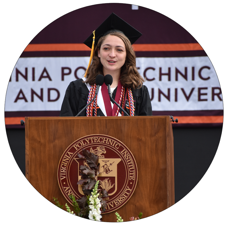 young woman in graduation grab speaks at podium