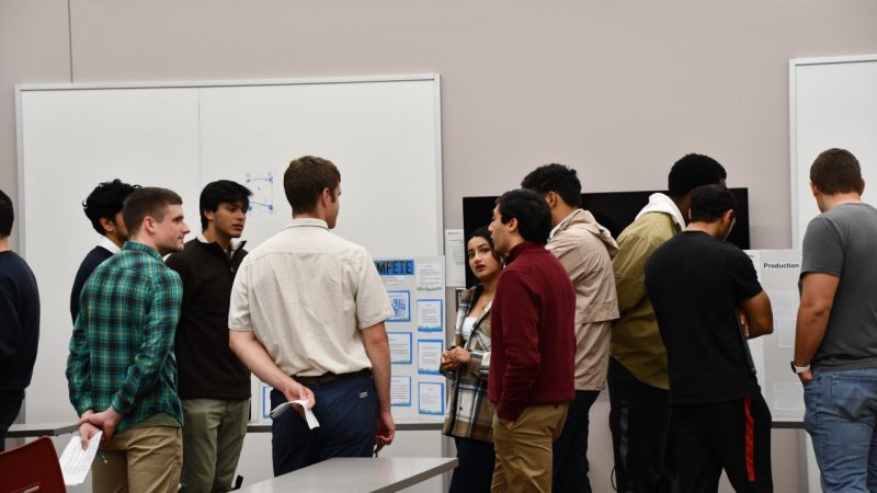 Group of students gather to discuss poster during judging of data competition.