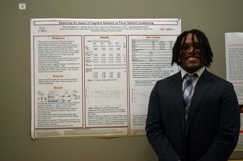 Smiling student stands next to poster