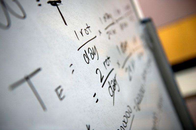 A white board with algorithms scrawled across it.  Students studying physics on Reading Day before final exams begin.