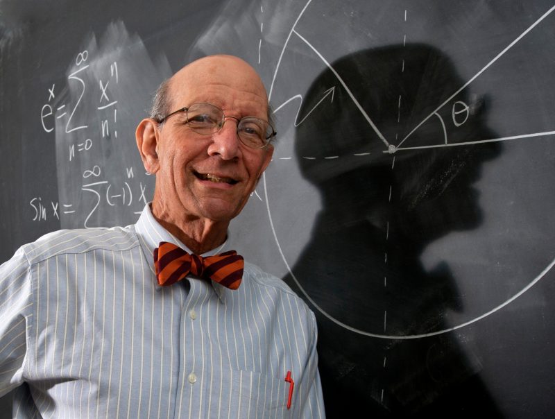 Dr. Brown stands in front of chalkboard with equations and his shadow creates a profile on the board.
