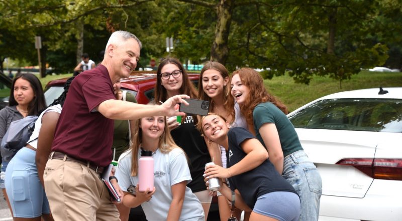 Kevin Pitts takes a selfie with undergraduate students outside