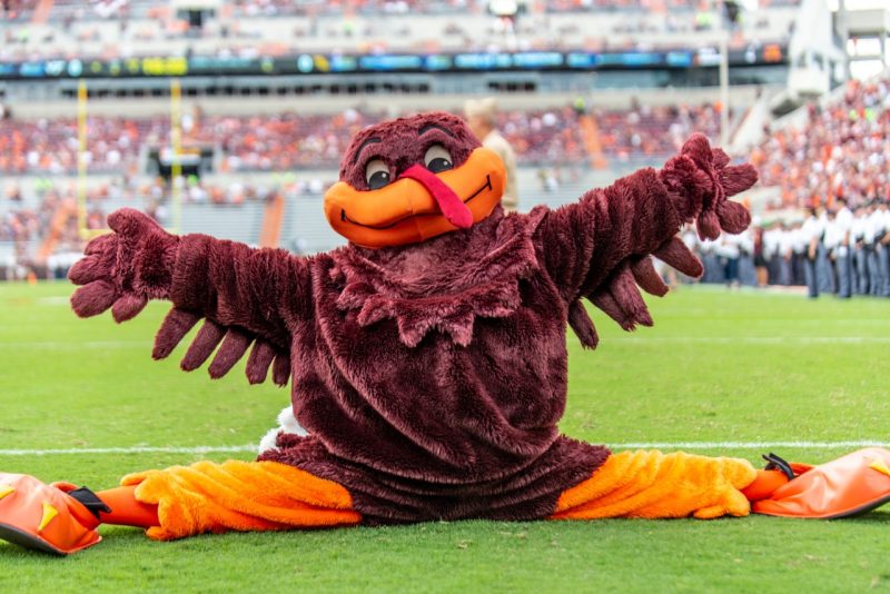 the Hokie Bird does the spilts on the field in Lane Stadium with arms spread wide 